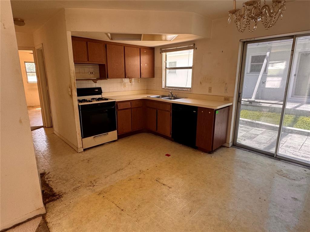 A kitchen with wood cabinets, a white stove, a black dishwasher, and worn vinyl flooring — 12400 PARK BOULEVARD UNIT 625, SEMINOLE, FL
