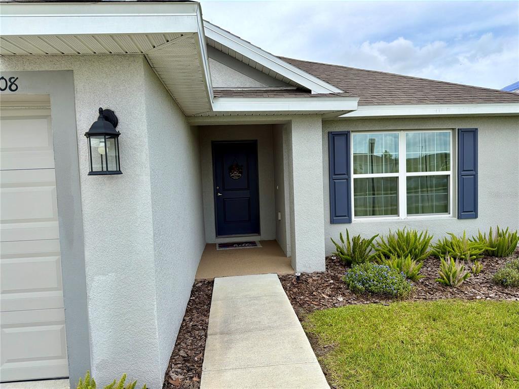 A concrete walkway leads to the blue front door of a light-colored stucco house — 2108 CARTGATE LANE, WINTER HAVEN, FL
