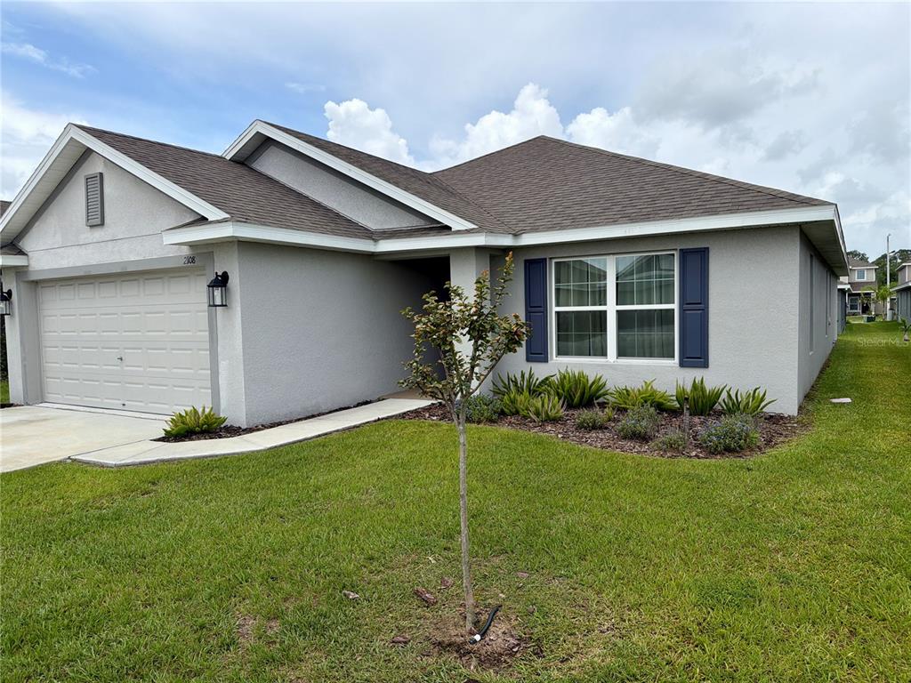 A single-story house with a gray stucco exterior, a two-car garage, and blue window shutters — 2108 CARTGATE LANE, WINTER HAVEN, FL