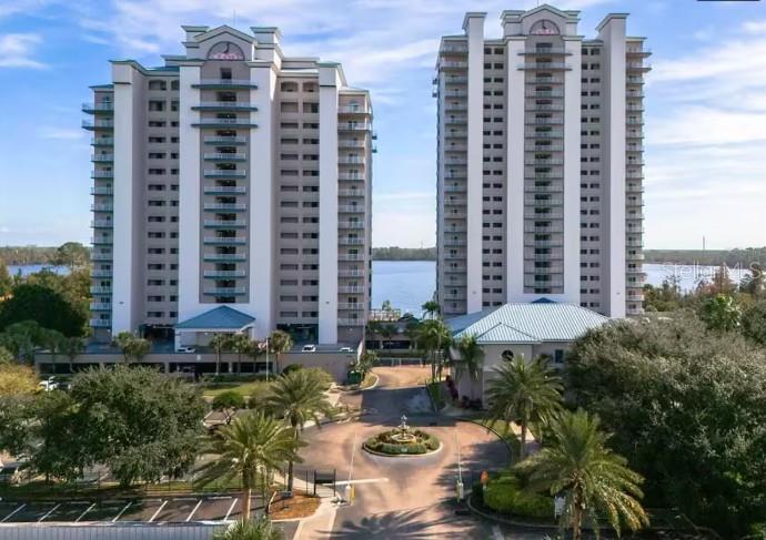 An aerial view shows two tall residential towers flanking a circular driveway with a central fountain — 13415 BLUE HERON BEACH DRIVE UNIT 403, ORLANDO, FL