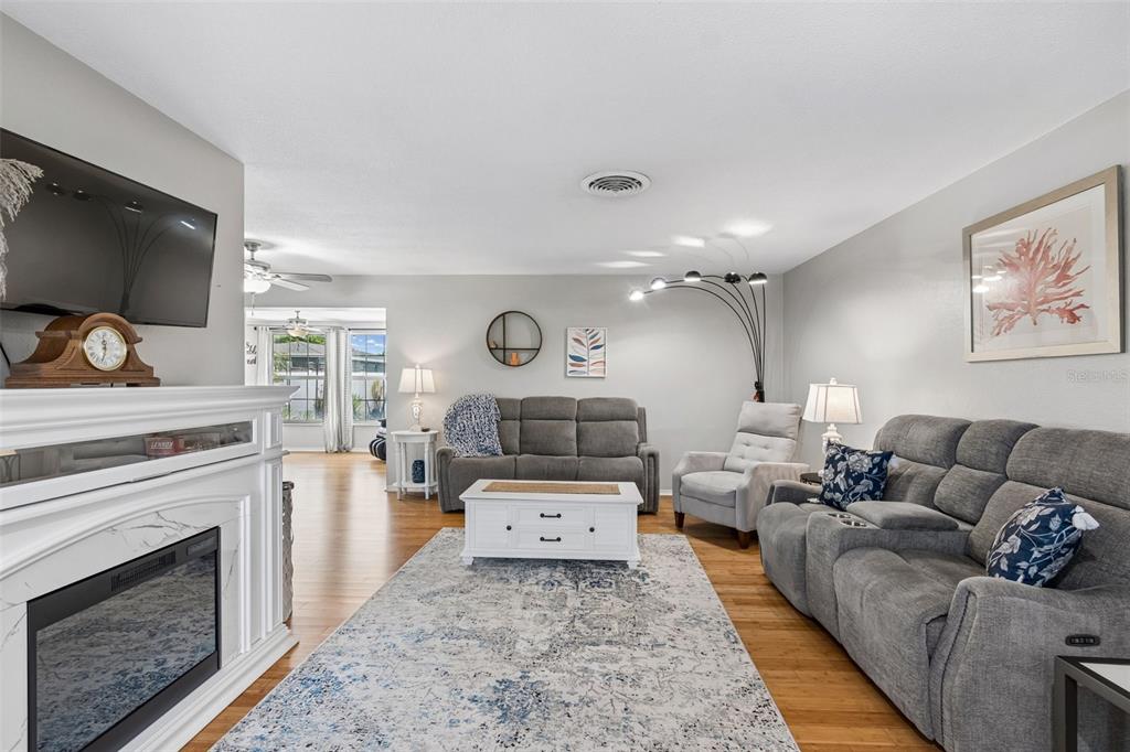 A living room features a fireplace, gray sofas, a white coffee table, and hardwood floors — 1229 GRENADA AVENUE, CLEARWATER, FL