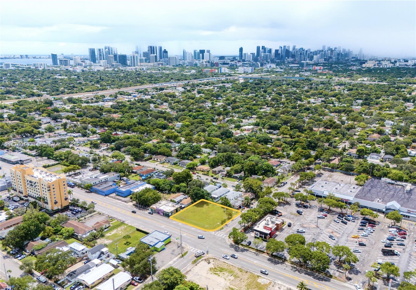 An aerial view shows a vacant rectangular lot highlighted in yellow near a city skyline — 1090 NW 54th St, Miami FL 33127, MIAMI, FL
