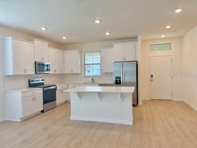 A modern kitchen features white cabinetry, stainless steel appliances, and a central island — 16840 HOBE SOUND COURT, WINTER GARDEN, FL