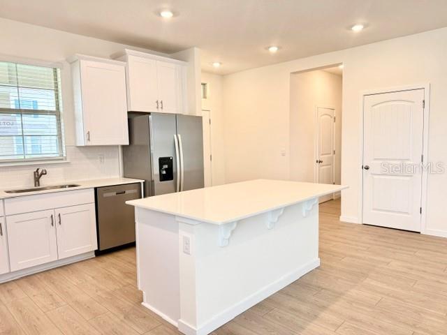 A modern kitchen features white cabinetry, stainless steel appliances, and a central island — 16840 HOBE SOUND COURT, WINTER GARDEN, FL