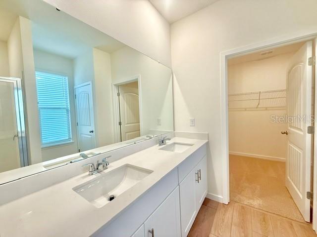 A bathroom features a double vanity with a large mirror and an adjacent walk-in closet — 16840 HOBE SOUND COURT, WINTER GARDEN, FL