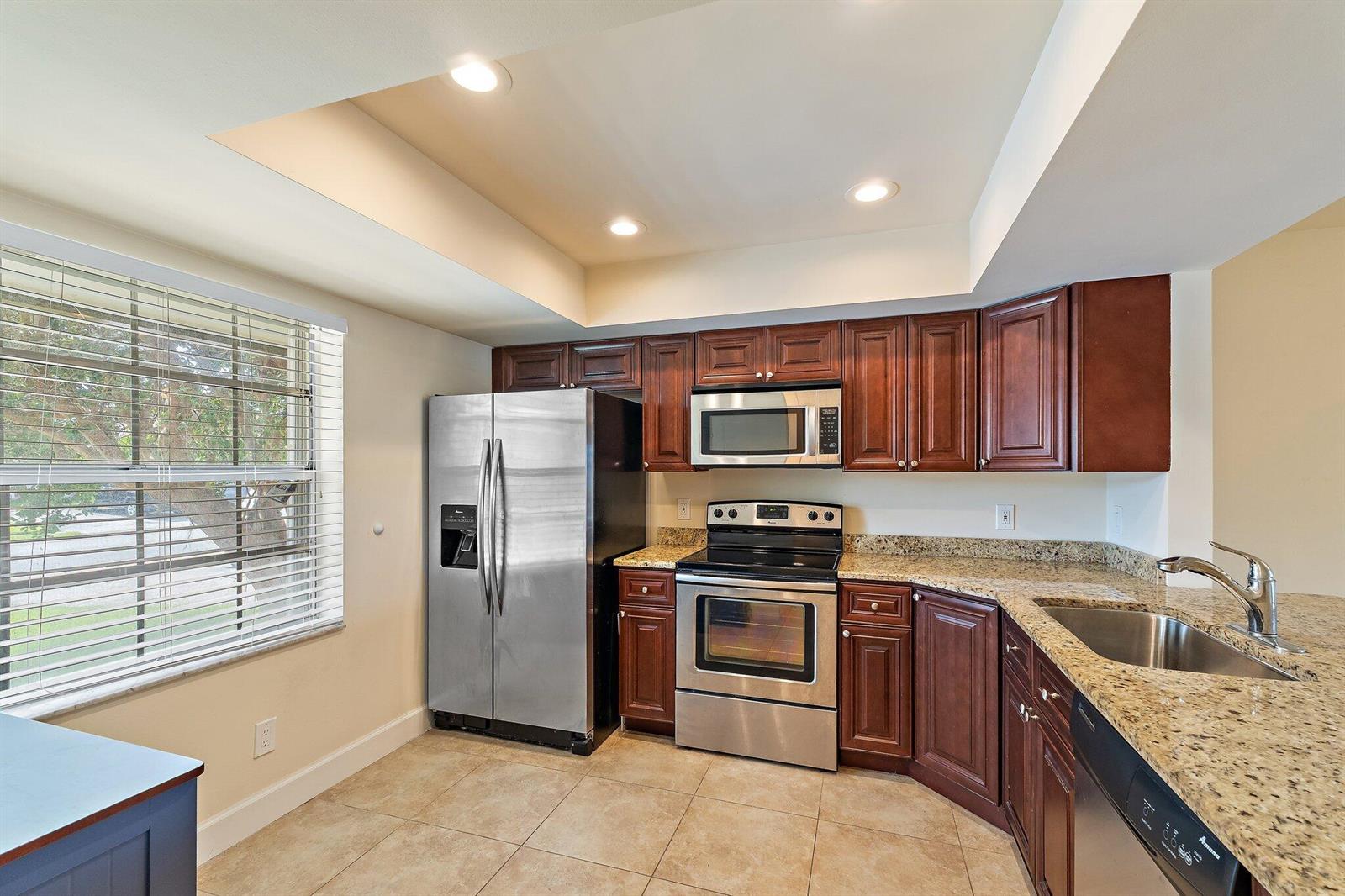 A kitchen with dark wood cabinets, granite countertops, stainless steel appliances, and tile flooring — 109 Doe Trail, Jupiter FL 33458, JUPITER, FL