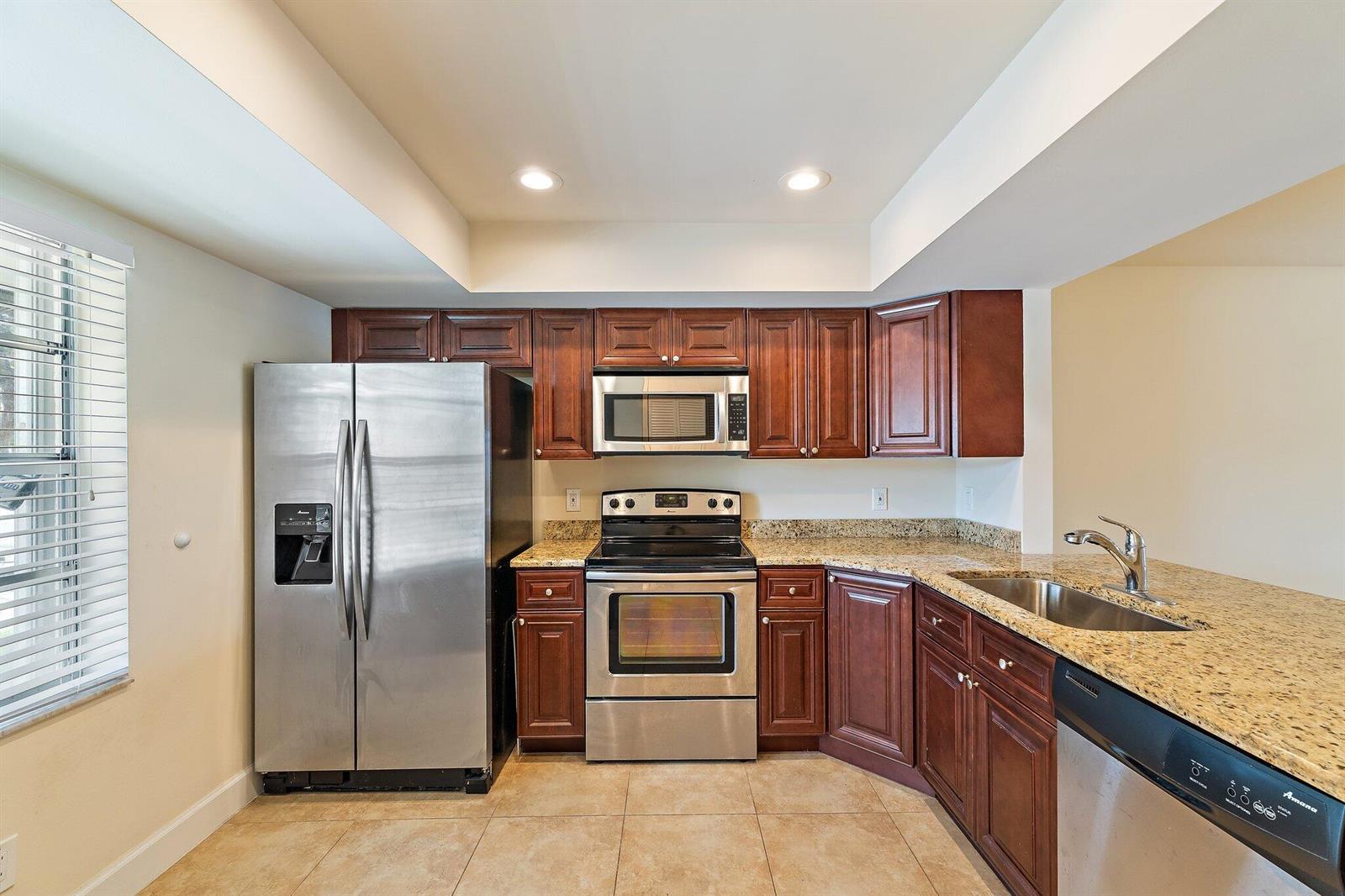 A kitchen features stainless steel appliances, dark wood cabinets, and granite countertops — 109 Doe Trail, Jupiter FL 33458, JUPITER, FL