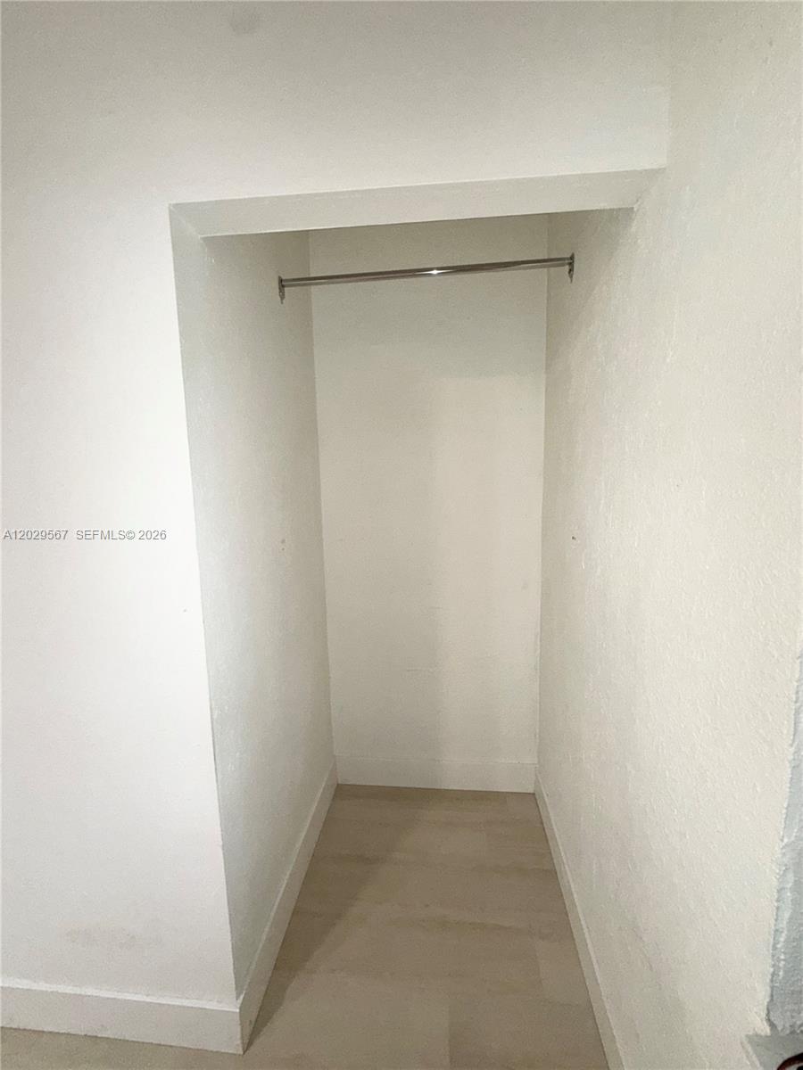 This is a small, empty closet with white walls, light flooring, and a metal hanging rod — 620 NE 160th St, Miami FL 33162, MIAMI, FL