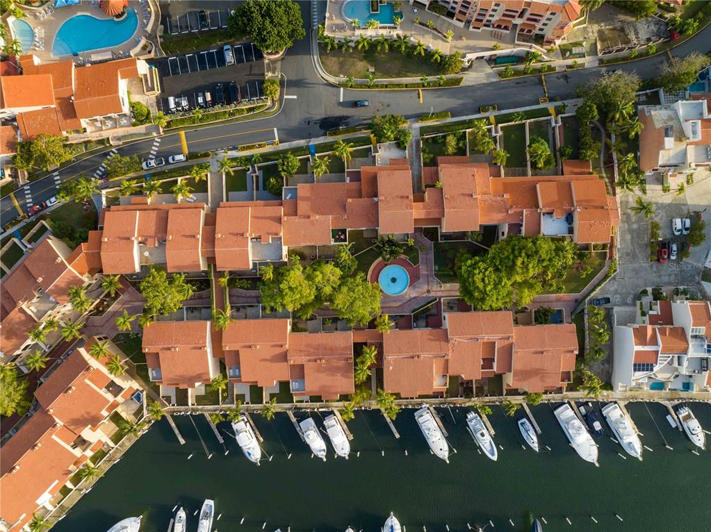 An aerial view shows a residential complex with terracotta roofs, a central pool, and boat slips — 1009 HARBOURSIDE, HUMACAO, PR