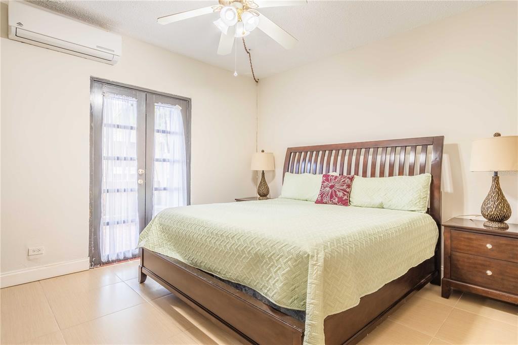 A bedroom features a king bed, a ceiling fan, a wall-mounted air conditioner, and French doors — 1009 HARBOURSIDE, HUMACAO, PR