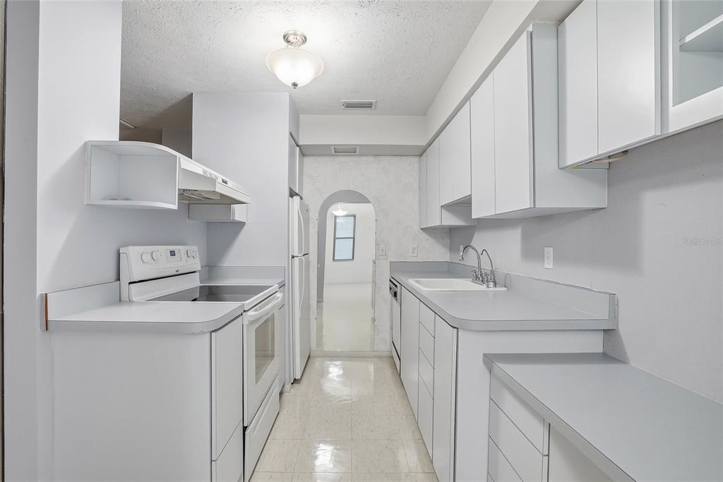 A galley-style kitchen features white cabinets, light gray countertops, and white appliances — 1026 W RAMBLA STREET, TAMPA, FL