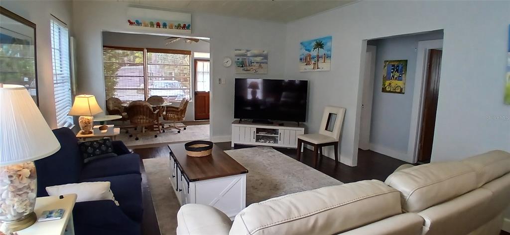 A living room features a dark blue sofa, a white coffee table, and a television — 1209 BAY PALM BOULEVARD, INDIAN ROCKS BEACH, FL