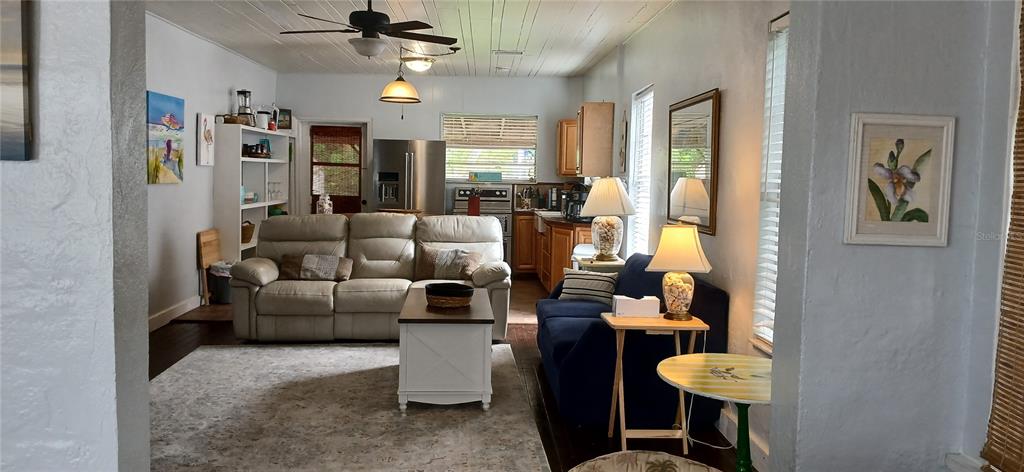 An open-concept living room features a beige sofa, a blue loveseat, and a kitchen area — 1209 BAY PALM BOULEVARD, INDIAN ROCKS BEACH, FL