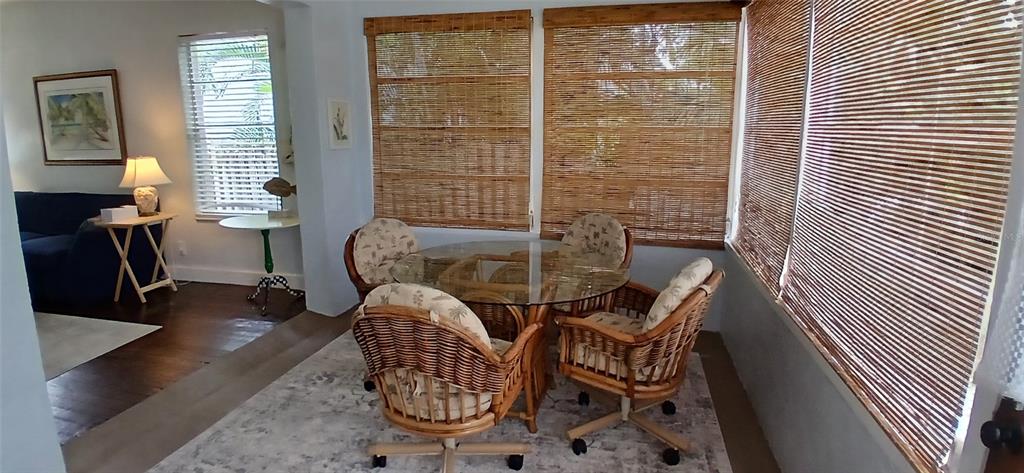 A sunroom features a glass-topped dining table with wicker chairs and bamboo window shades — 1209 BAY PALM BOULEVARD, INDIAN ROCKS BEACH, FL