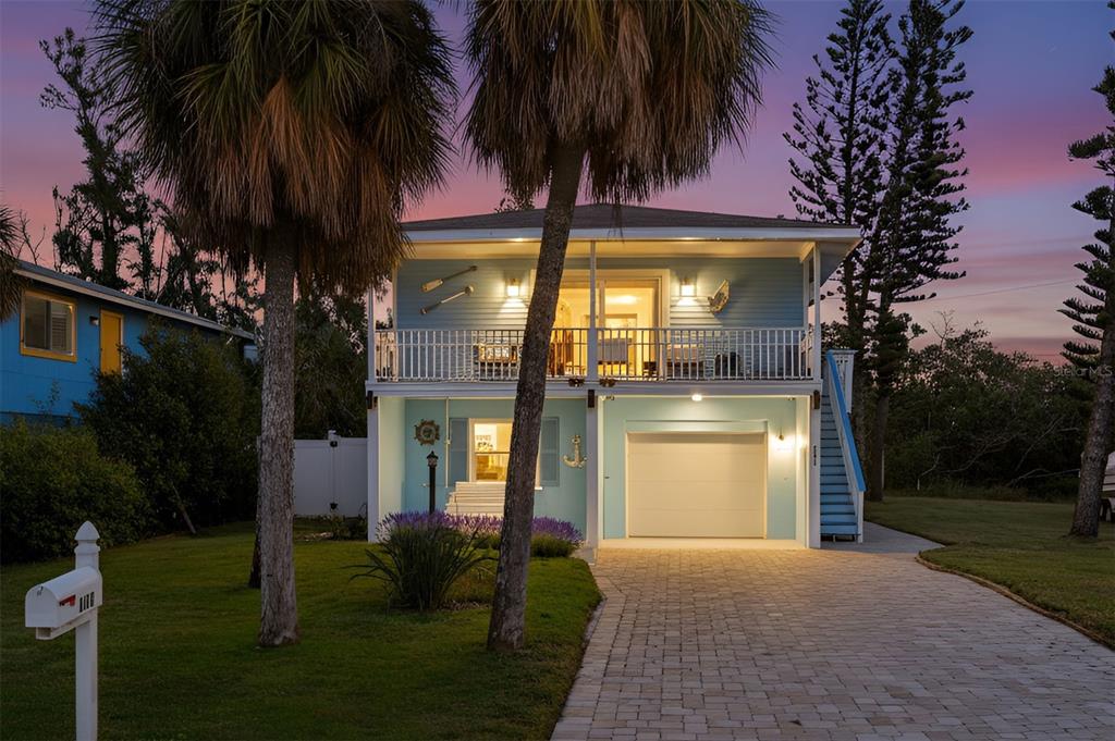 A two-story light blue house with a balcony, garage, and palm trees at dusk — 2915 AVENUE C, HOLMES BEACH, FL
