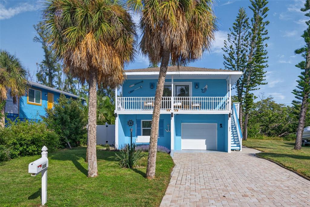 A two-story blue house with a white balcony, garage, and palm trees in the front yard — 2915 AVENUE C, HOLMES BEACH, FL