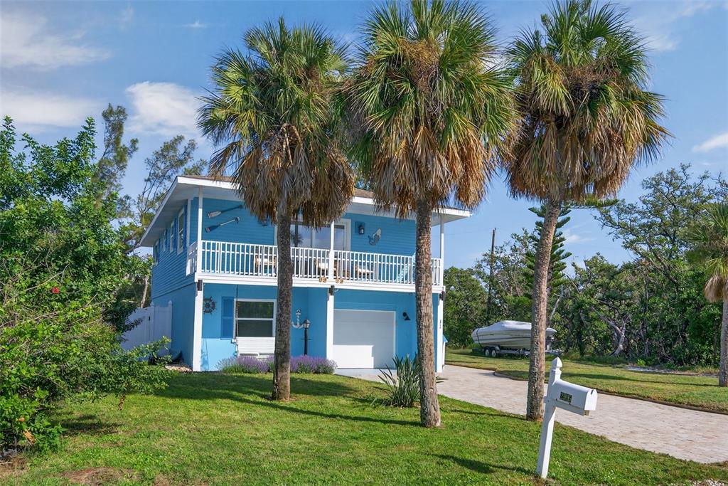 A two-story blue house with a white balcony, garage, and three palm trees in front — 2915 AVENUE C, HOLMES BEACH, FL