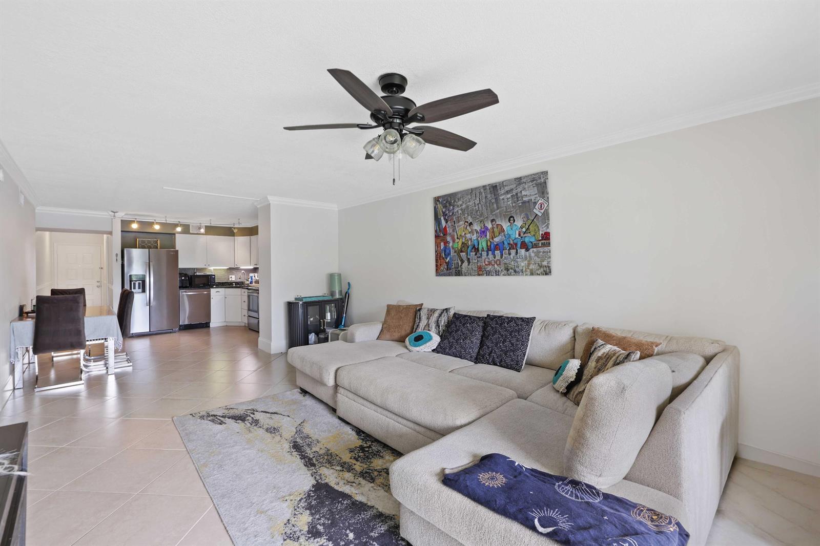 A living room with a beige sectional sofa, a patterned area rug, and an open kitchen — 3020 Florida Boulevard # c, Delray Beach FL 33483, DELRAY BEACH, FL