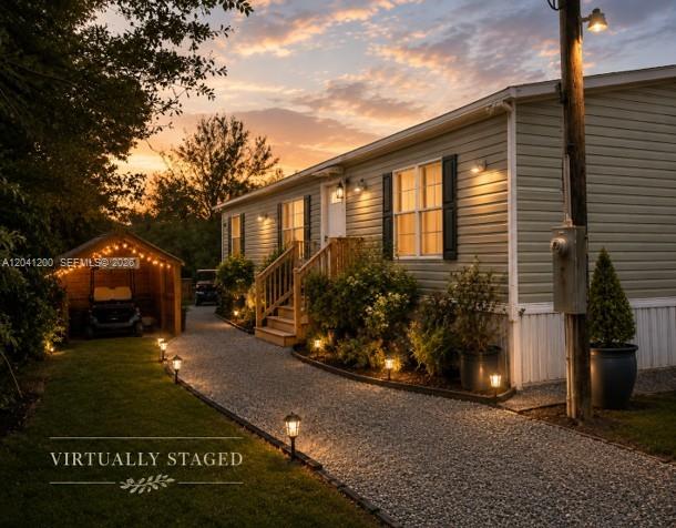 A gravel path leads to a light-colored mobile home with a wooden porch at sunset — 640 N Kennel St, Clewiston FL 33440, CLEWISTON, FL