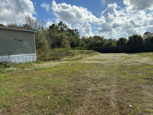 A side view of a light-colored mobile home sits next to a large, grassy lot — 640 N Kennel St, Clewiston FL 33440, CLEWISTON, FL