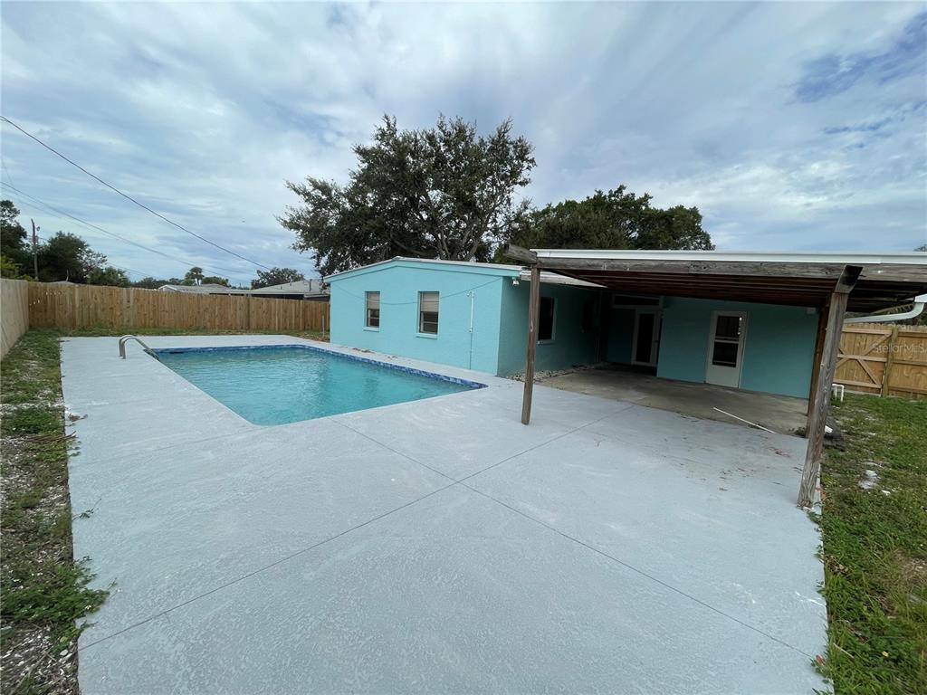 A backyard features a swimming pool, a concrete patio, and a covered porch area — 2001 PRINCETON AVENUE, BRADENTON, FL