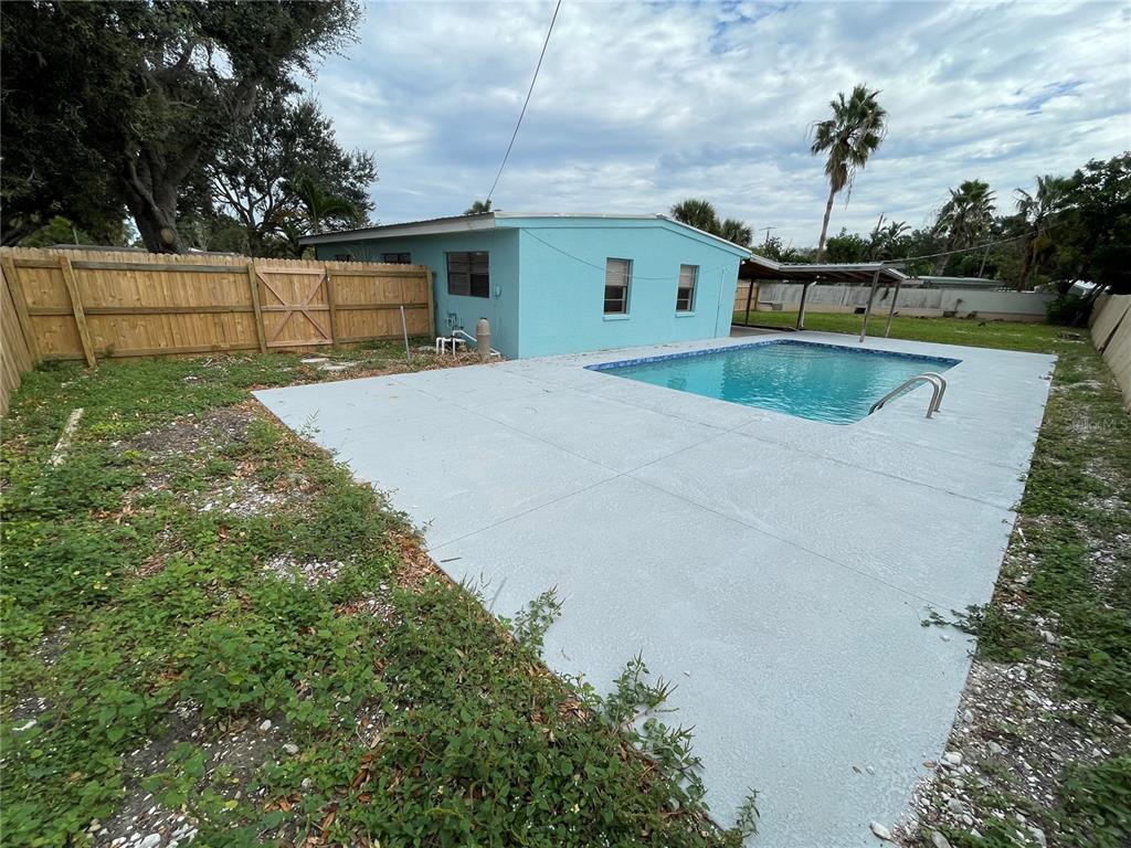 A light blue house features a swimming pool and a concrete patio in the backyard — 2001 PRINCETON AVENUE, BRADENTON, FL