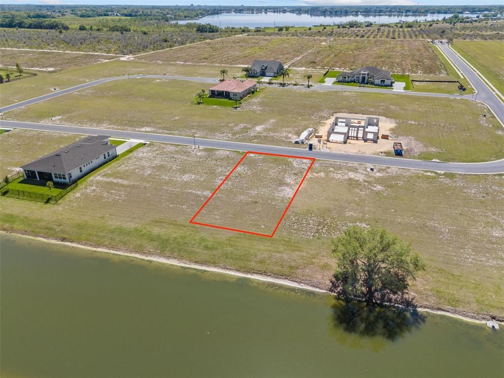 An aerial view shows a vacant residential lot outlined in red bordering a lake — 345 ADAMS VIEW LANE, AUBURNDALE, FL