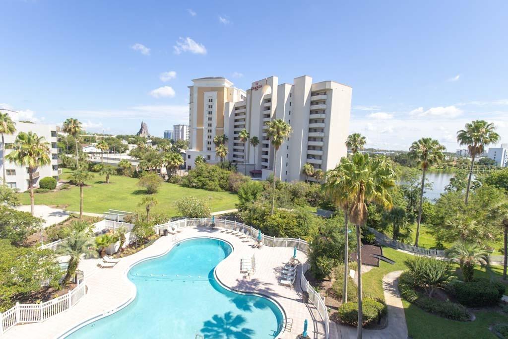 An elevated view of a swimming pool, palm trees, and a large hotel building — 6165 CARRIER DRIVE UNIT 1601, ORLANDO, FL