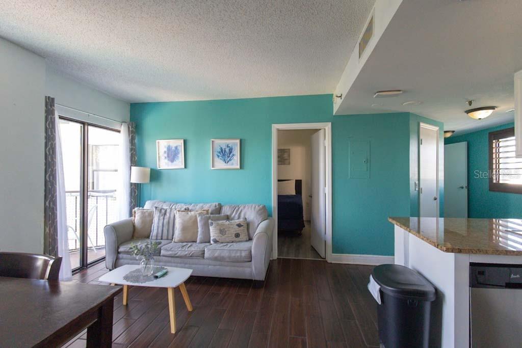 A living room with a teal accent wall, gray sofa, and dark wood flooring — 6165 CARRIER DRIVE UNIT 1601, ORLANDO, FL