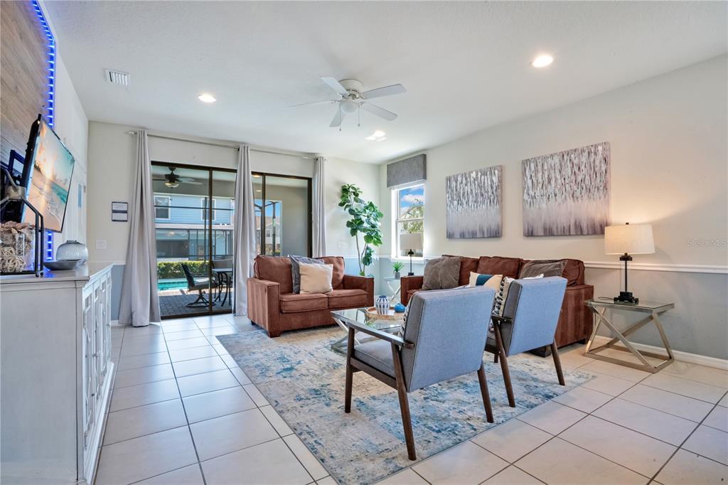 A living room features tile floors, a brown sectional, two gray chairs, and sliding doors — 8936 PRAGUE WAY, KISSIMMEE, FL