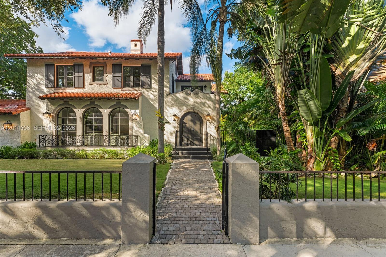 A two-story Mediterranean-style house features a tiled roof, arched windows, and a gated walkway — 547 NE 57th St, Miami FL 33137, MIAMI, FL