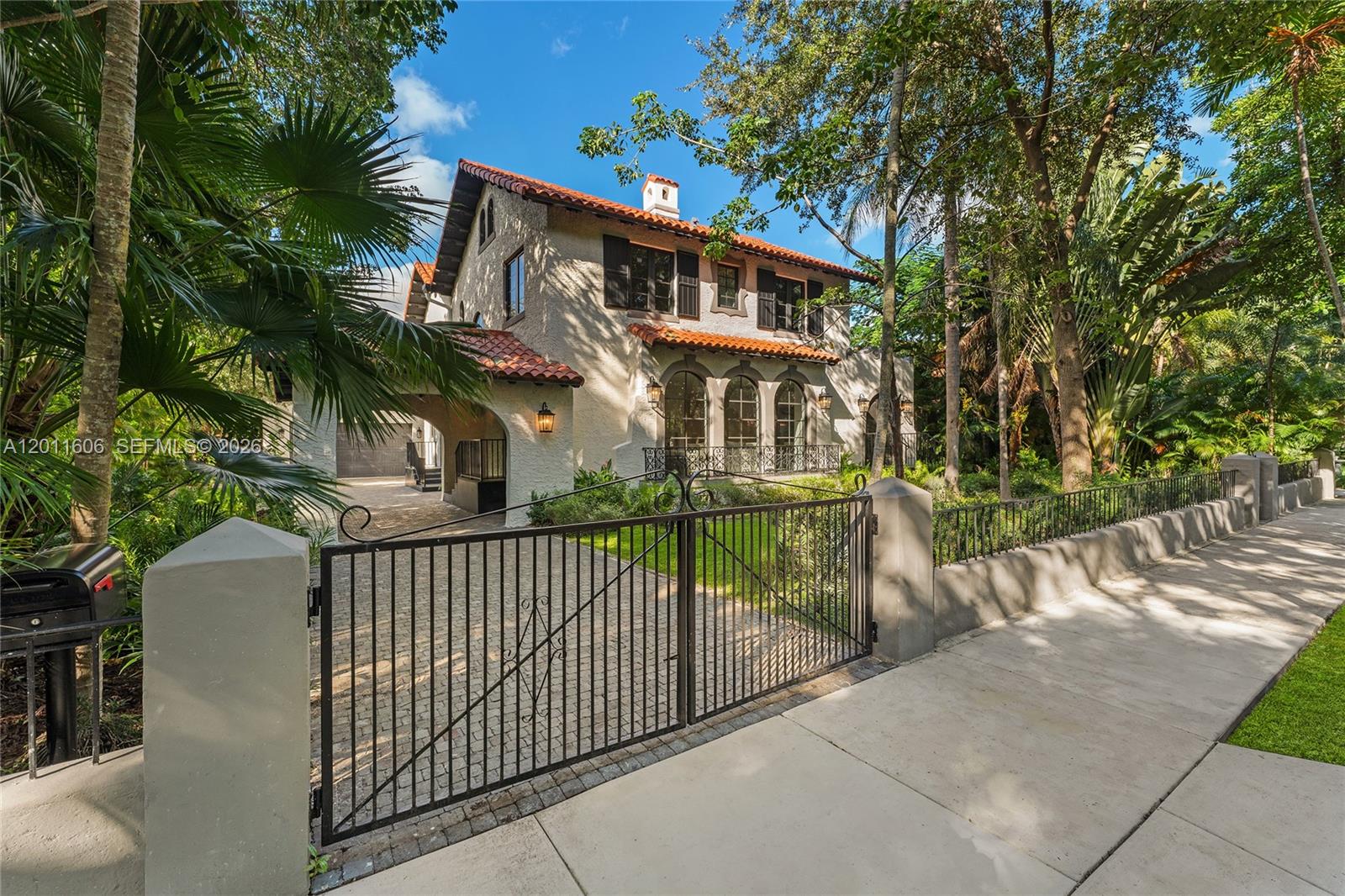 A two-story Mediterranean-style house with a tile roof sits behind a gated driveway — 547 NE 57th St, Miami FL 33137, MIAMI, FL