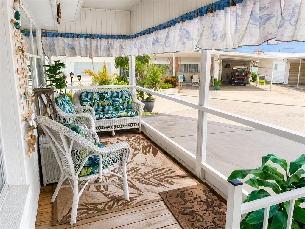 A screened-in porch features white wicker furniture, a patterned rug, and views of neighboring homes — 1613 MICHIGAN AVENUE, BRADENTON, FL