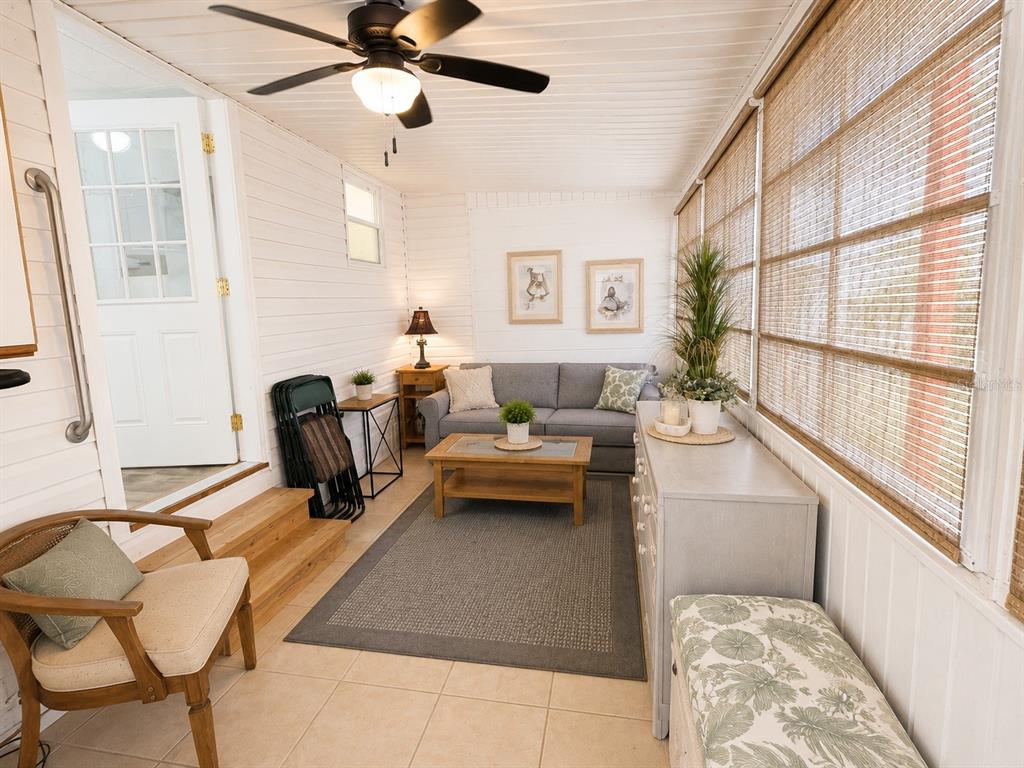A sunroom features a gray sofa, a wooden coffee table, tile floors, and bamboo window shades — 1613 MICHIGAN AVENUE, BRADENTON, FL