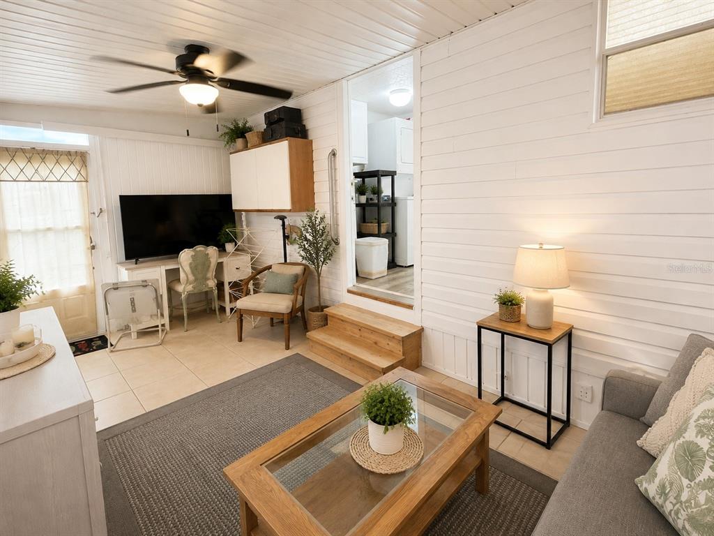 A sunroom features white paneled walls, tile flooring, a ceiling fan, and a glass-topped coffee table — 1613 MICHIGAN AVENUE, BRADENTON, FL