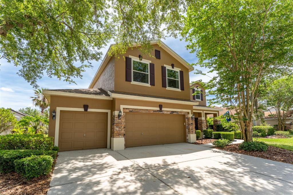 A two-story house with a tan exterior, stone accents, and a three-car garage — 6302 BRIDGEVISTA DRIVE, LITHIA, FL
