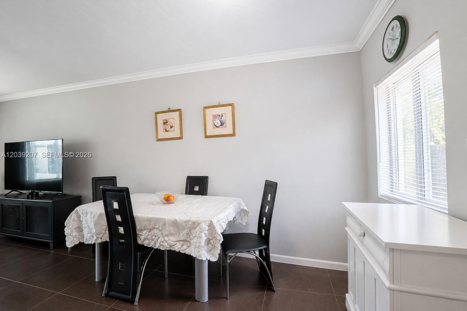 A dining area features a table with a white tablecloth, black chairs, and tile flooring — 521 NE 82nd Ter # 3, Miami FL 33138, MIAMI, FL
