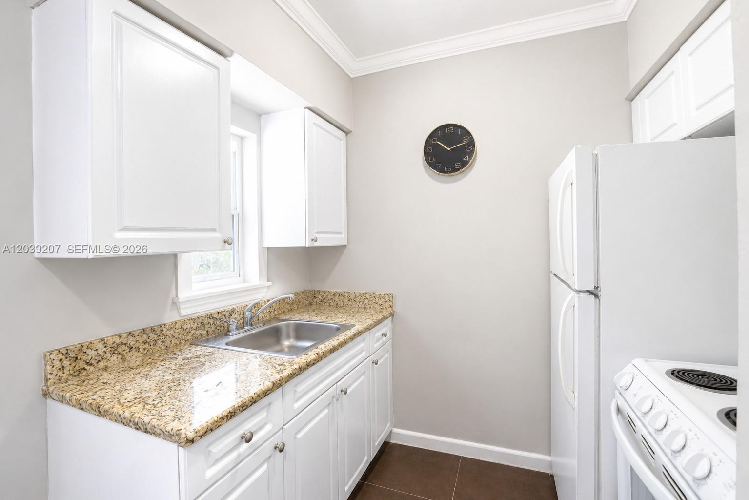 A kitchen features white cabinets, granite countertops, a stainless steel sink, and a wall clock — 521 NE 82nd Ter # 3, Miami FL 33138, MIAMI, FL