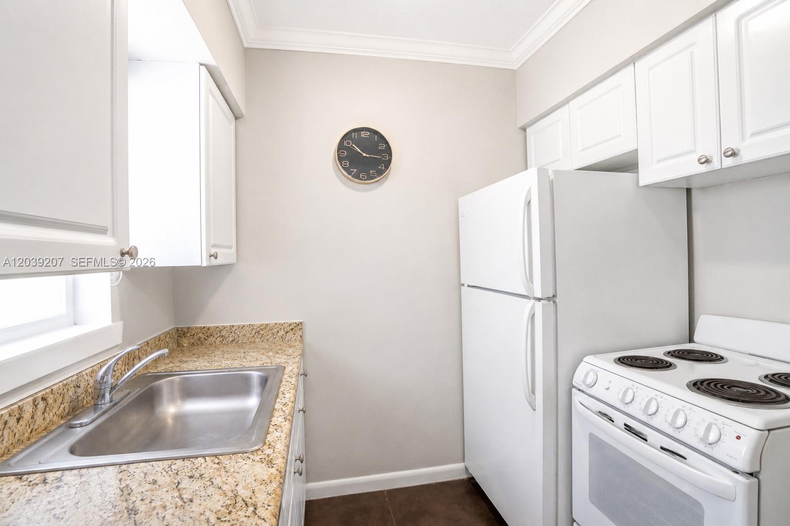 A kitchen features white cabinets, a stainless steel sink, granite countertops, and a white refrigerator — 521 NE 82nd Ter # 3, Miami FL 33138, MIAMI, FL