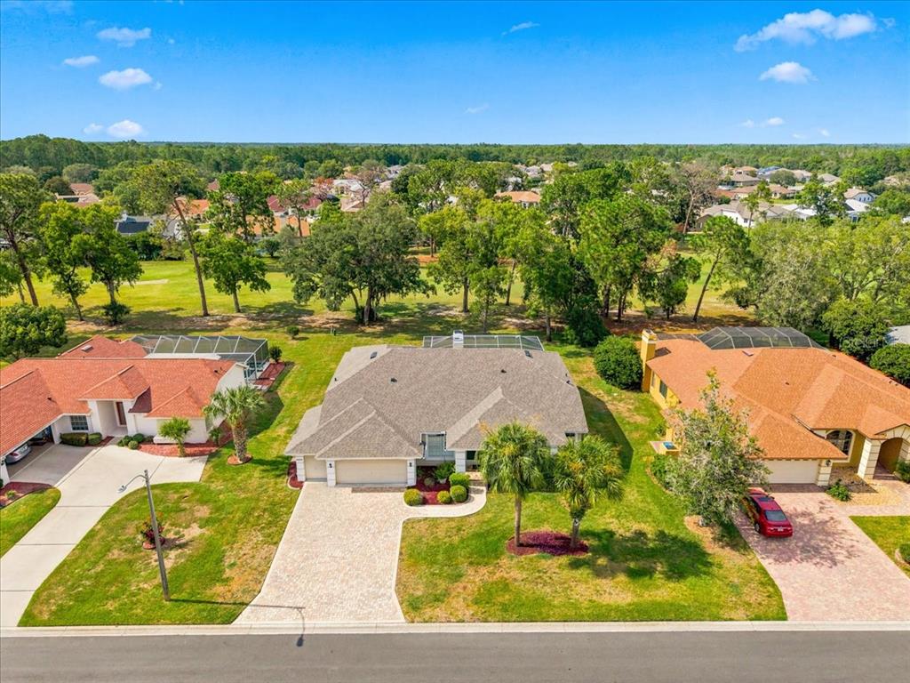 An aerial view of a suburban house with a paved driveway and a backyard pool enclosure — 9355 MERRIWEATHER DRIVE, WEEKI WACHEE, FL