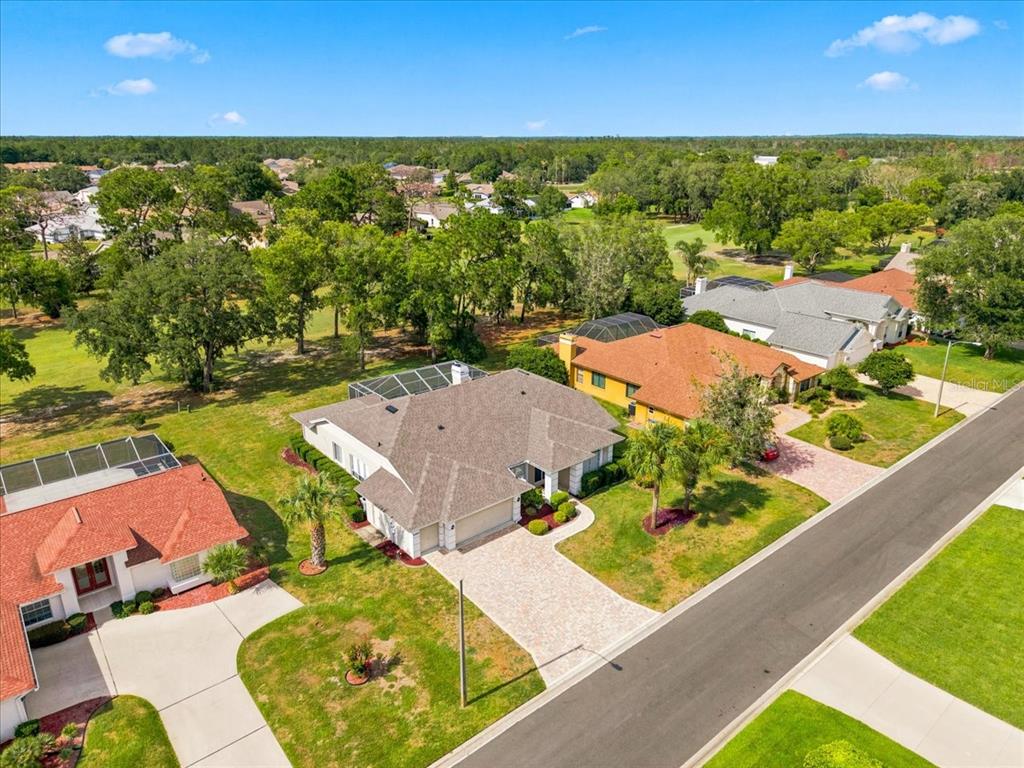 An aerial view shows a suburban house with a paved driveway and a screened-in pool — 9355 MERRIWEATHER DRIVE, WEEKI WACHEE, FL