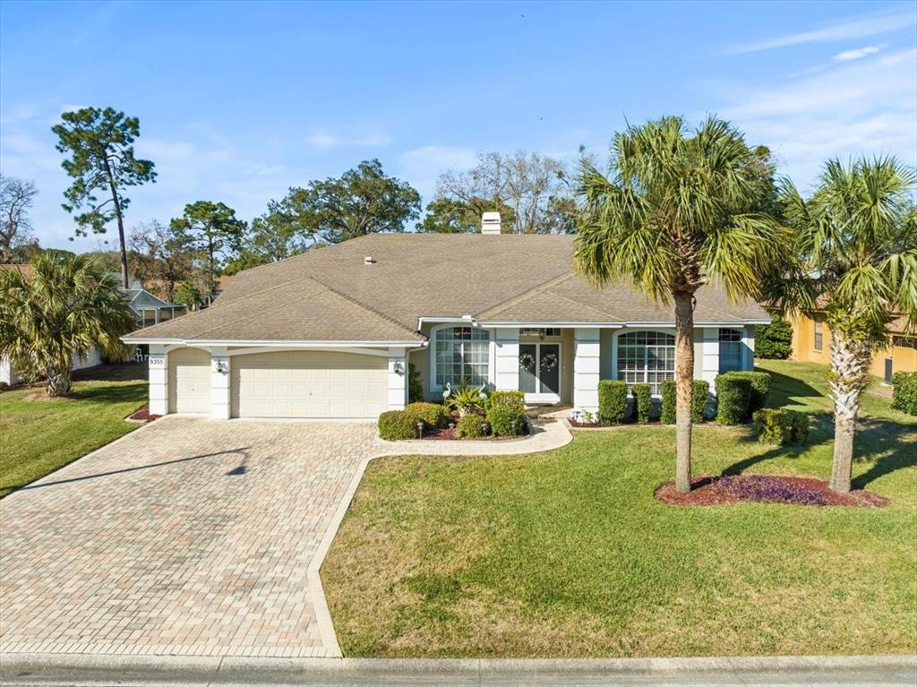 A single-story house with a paved driveway, a three-car garage, and palm trees — 9355 MERRIWEATHER DRIVE, WEEKI WACHEE, FL