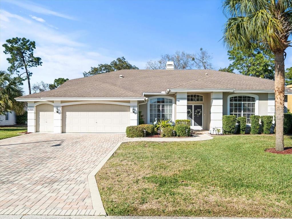 A single-story house with a beige stucco exterior, a paved driveway, and a shingled roof — 9355 MERRIWEATHER DRIVE, WEEKI WACHEE, FL