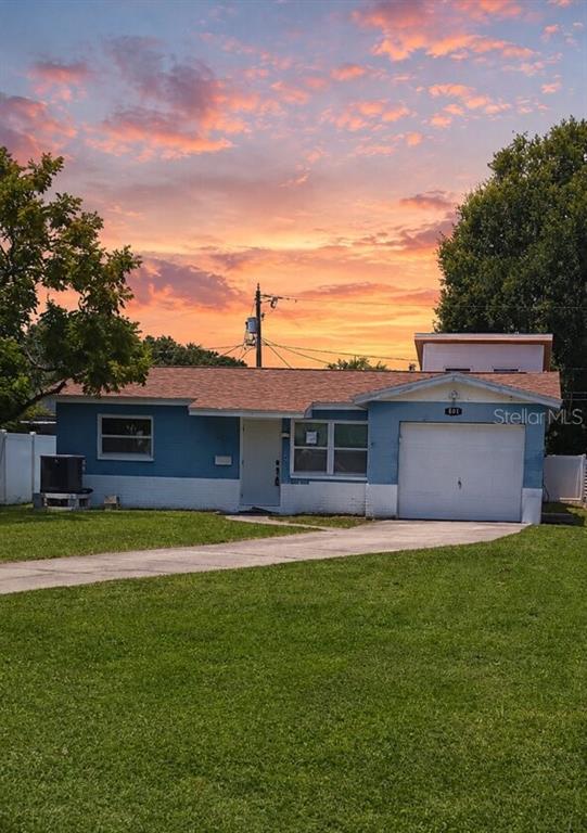 A blue, single-story house with a white garage door and a grassy front yard — 501 PALM AVENUE N, ST PETERSBURG, FL