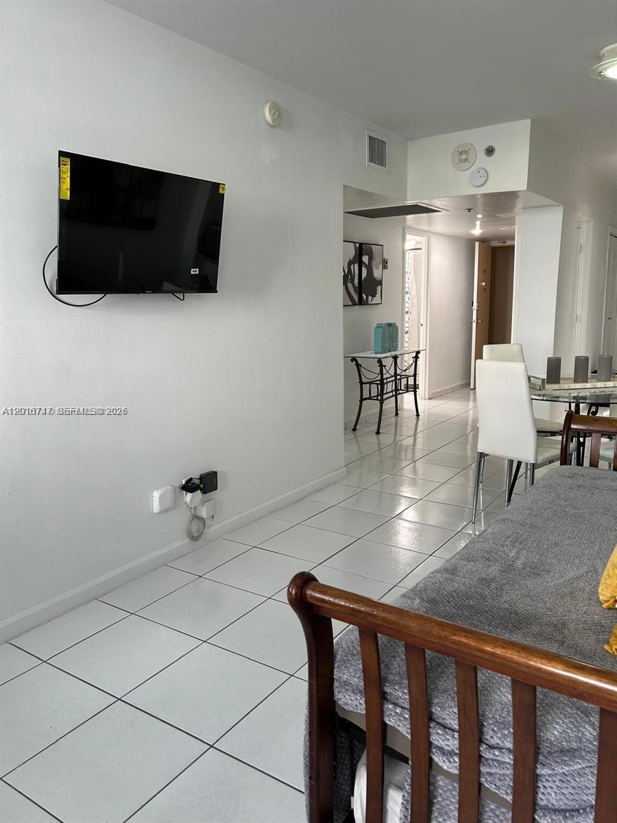 A white-walled room features a wall-mounted television, tiled flooring, and a view into a hallway — 100 Lincoln Rd # 437, Miami Beach FL 33139, MIAMI BEACH, FL