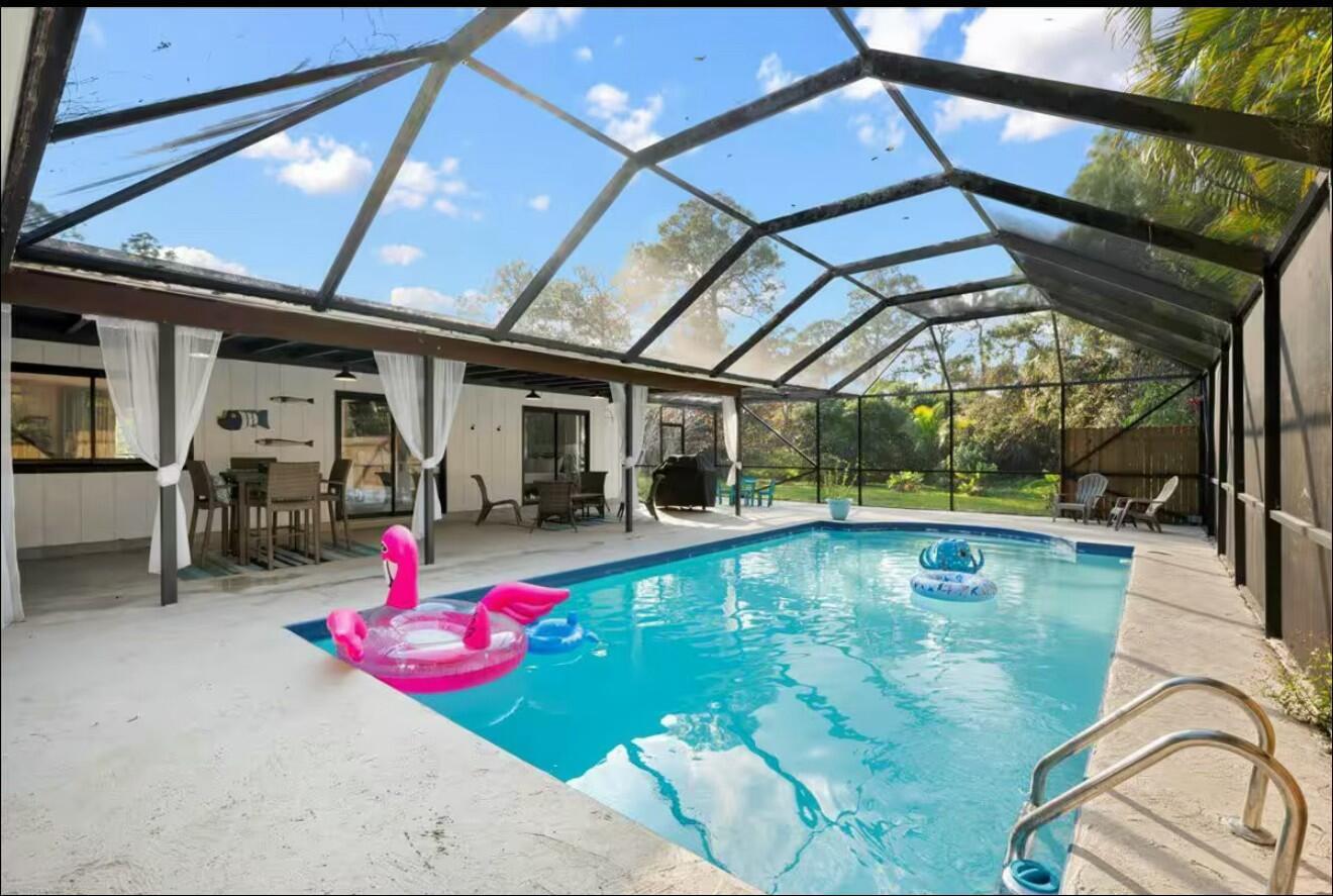 A screened-in patio features a rectangular swimming pool with a pink flamingo float — 11405 N 175th Rd Road N, FL 33478, FL