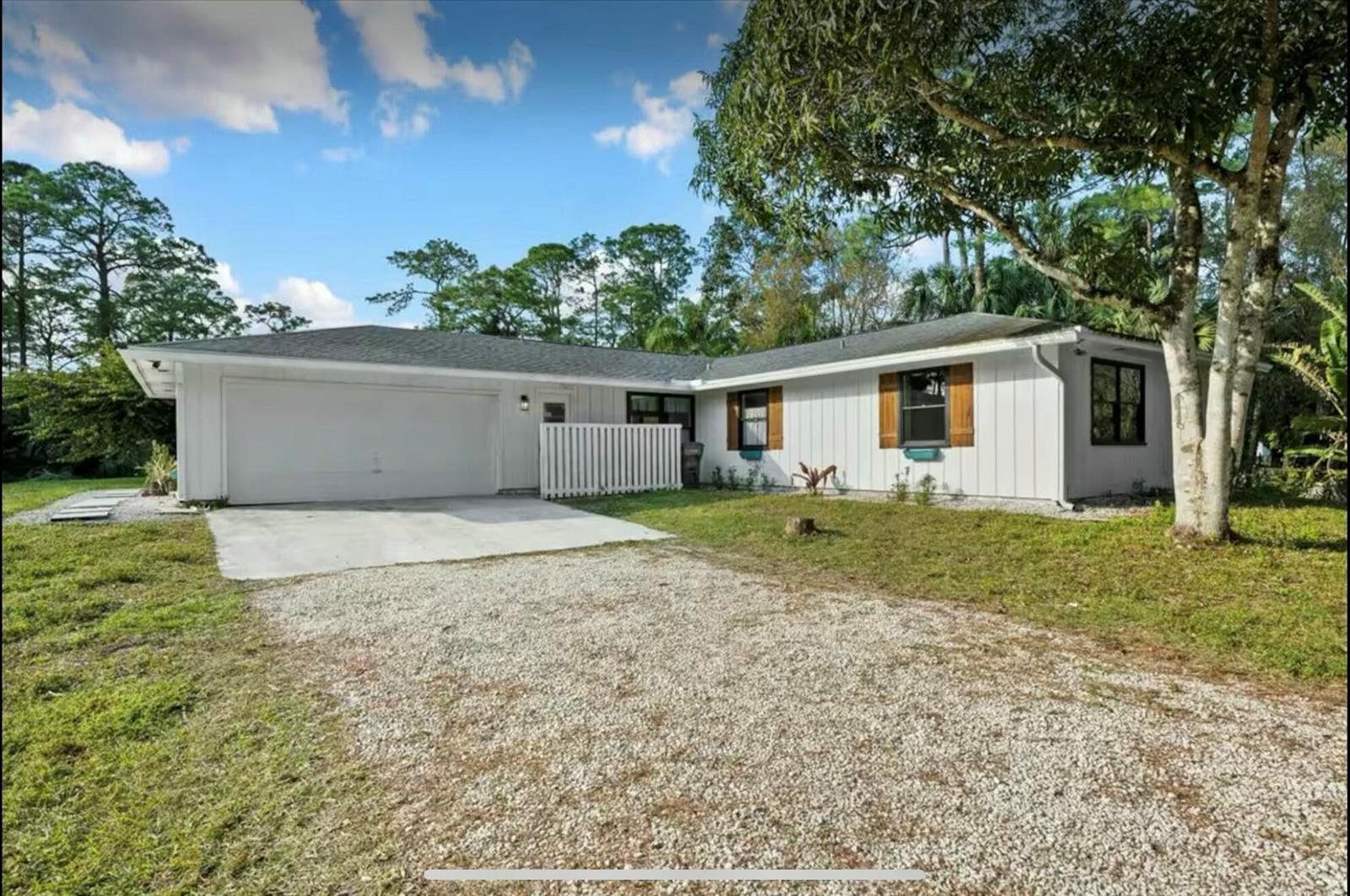 A single-story house with white vertical siding, a gravel driveway, and a two-car garage — 11405 N 175th Rd Road N, FL 33478, FL