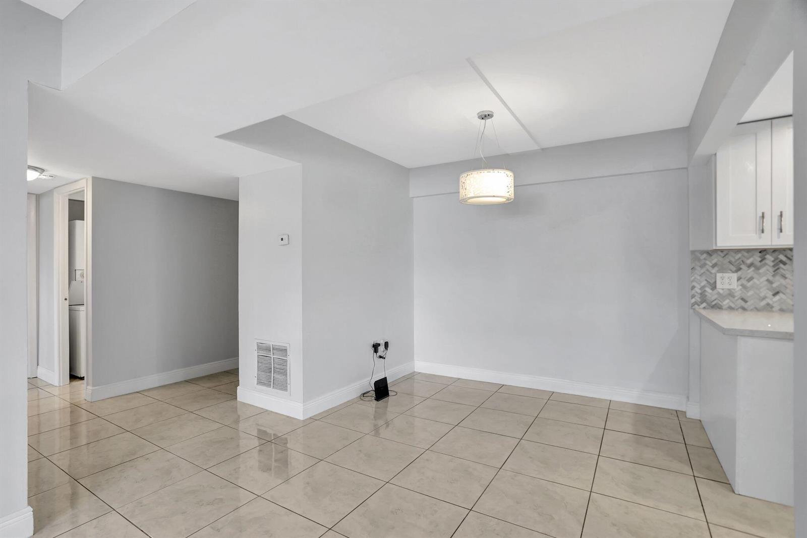 An empty dining area features light-colored tile flooring, a pendant light, and white walls — 4156 Inverrary Drive # 111, Lauderhill FL 33319, LAUDERHILL, FL