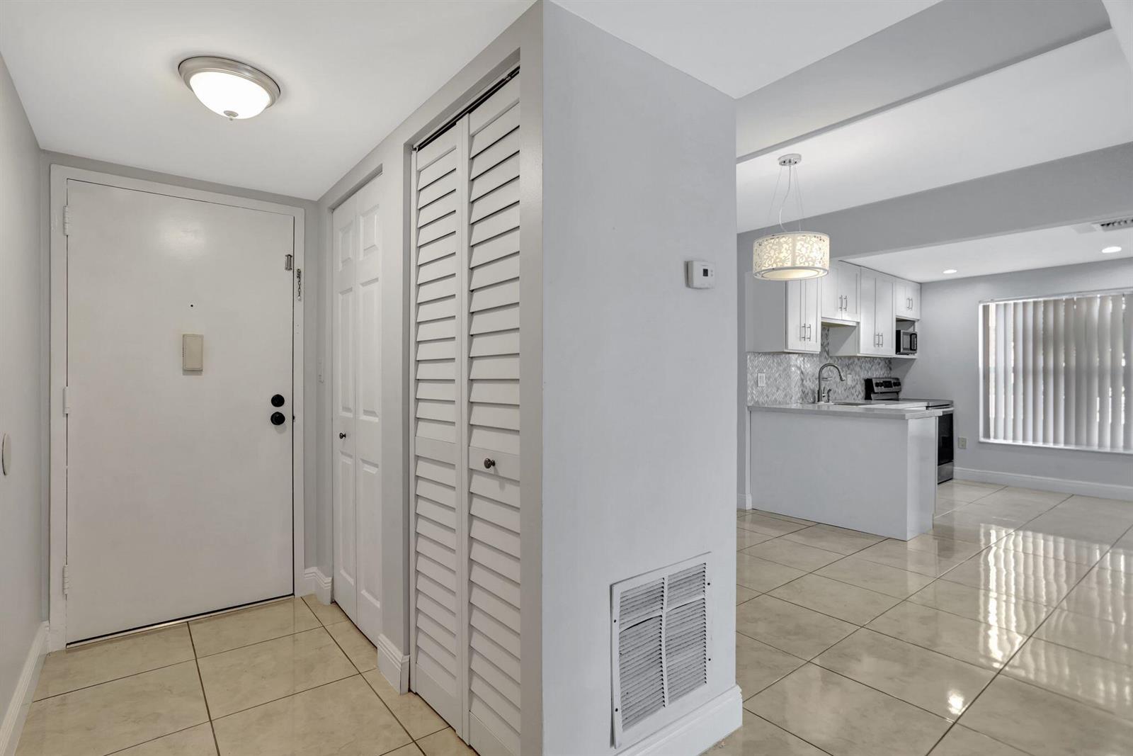 A tiled entryway leads to a white kitchen with a breakfast bar and pendant lighting — 4156 Inverrary Drive # 111, Lauderhill FL 33319, LAUDERHILL, FL