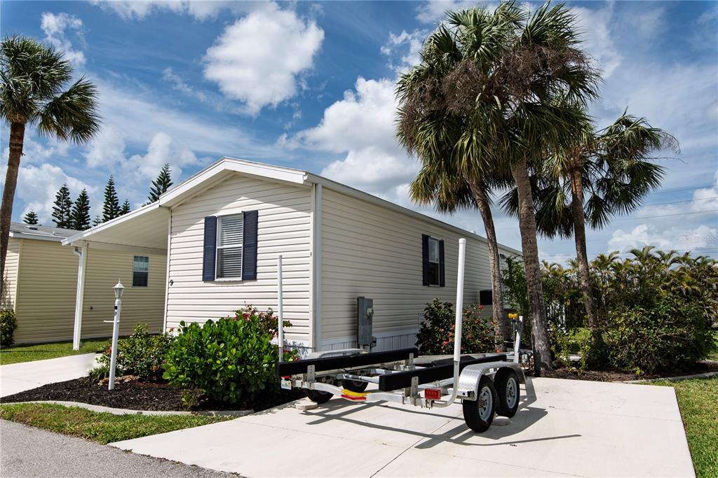 A light-colored mobile home with a boat trailer parked on a concrete driveway — 9 HOLLAND DRIVE, PUNTA GORDA, FL